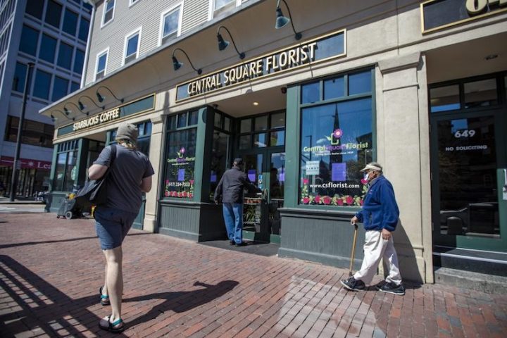 A prospectve patron attempts to open the front door of Central Square Florist, which is not open for in-store or curbside business, but only for contactless delivery. (Jesse Costa/WBUR)