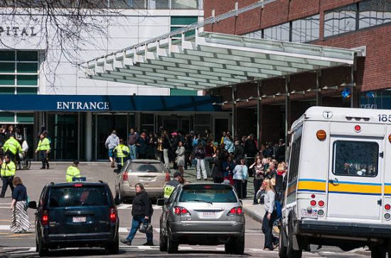 Boston, Massachusetts, United States - April 18, 2013: Several people crowd in front of the Massachusetts General Hospital in Boston, while President Barack Obama is visiting the wounded during the attack in Boston on April 15. Several police control the situation.